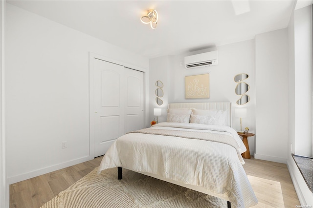 bedroom featuring an AC wall unit, a closet, and light wood-type flooring