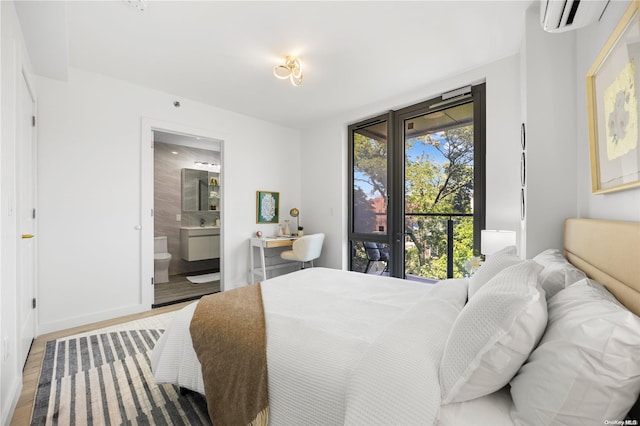 bedroom featuring hardwood / wood-style floors, a wall unit AC, and connected bathroom