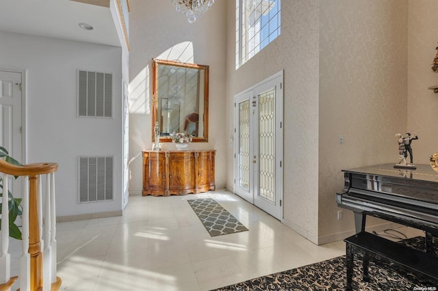 entryway featuring a notable chandelier, light tile patterned floors, and a towering ceiling