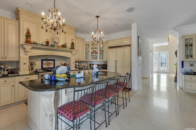 kitchen featuring a breakfast bar area, backsplash, a center island with sink, and cream cabinetry