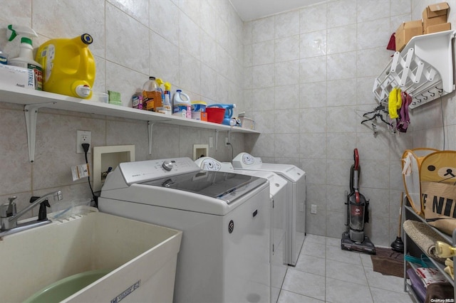 laundry area featuring washer and dryer, light tile patterned floors, tile walls, and sink