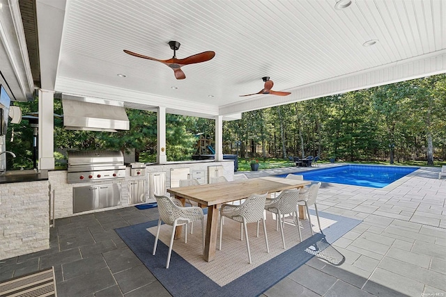 view of swimming pool with a grill, ceiling fan, a patio area, and exterior kitchen