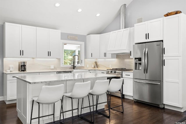 kitchen featuring white cabinetry, stainless steel appliances, a kitchen breakfast bar, vaulted ceiling, and a kitchen island