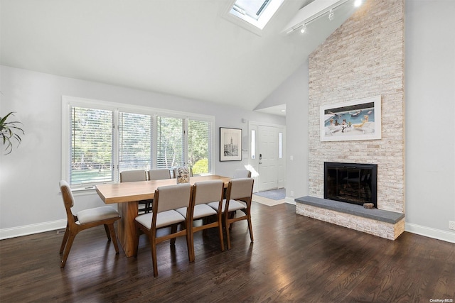 dining area with a fireplace, a skylight, high vaulted ceiling, and dark wood-type flooring