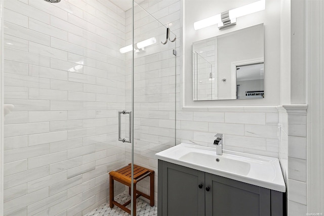 bathroom featuring vanity, a shower with shower door, and tile walls