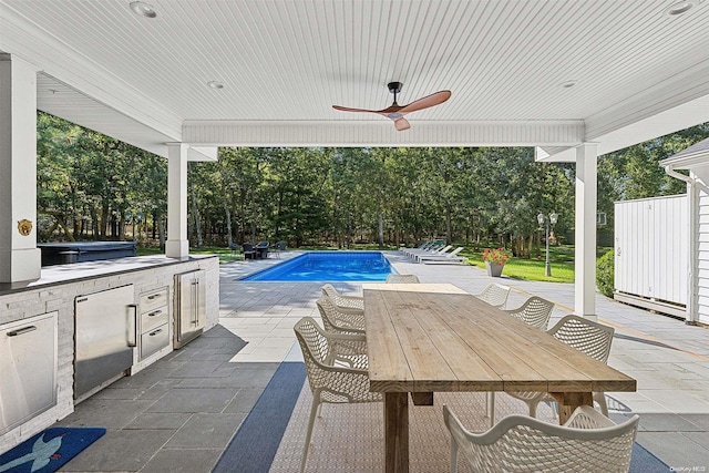 view of pool featuring ceiling fan, a patio, and an outdoor kitchen