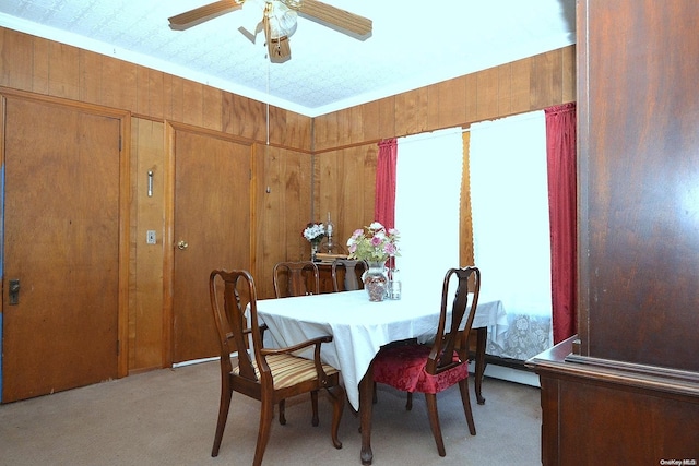 carpeted dining space with ceiling fan and wooden walls