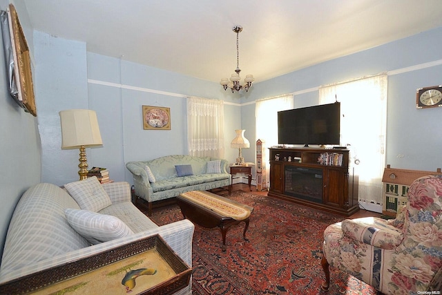 living room with baseboard heating, wood-type flooring, and a notable chandelier