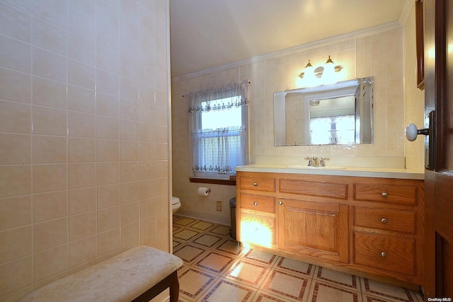 bathroom featuring vanity, toilet, ornamental molding, and tile walls