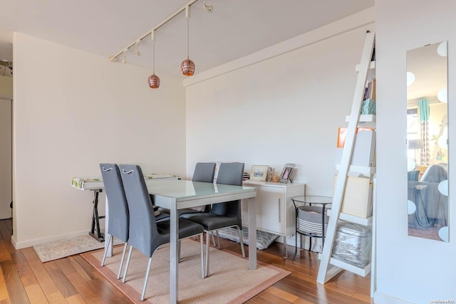 dining area with rail lighting and hardwood / wood-style flooring