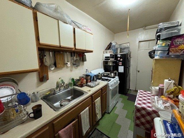 kitchen featuring white cabinetry, black refrigerator, white gas stove, and sink