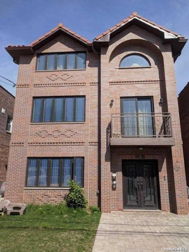 view of front of property featuring a balcony, a front lawn, and french doors