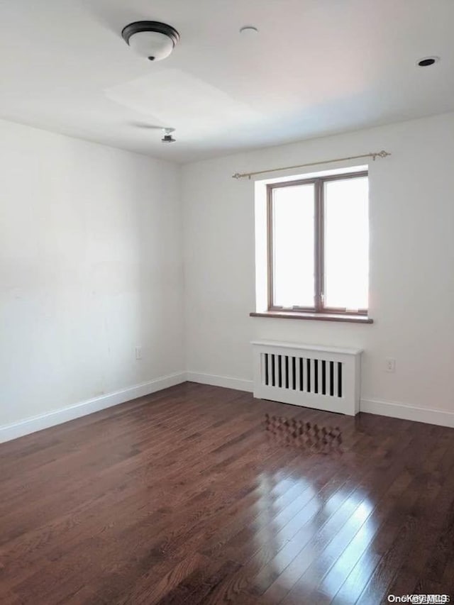 empty room with radiator and dark wood-type flooring