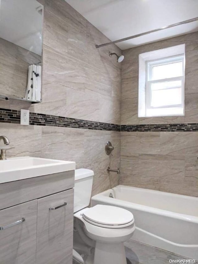 full bathroom with vanity, tiled shower / bath combo, tile walls, and toilet