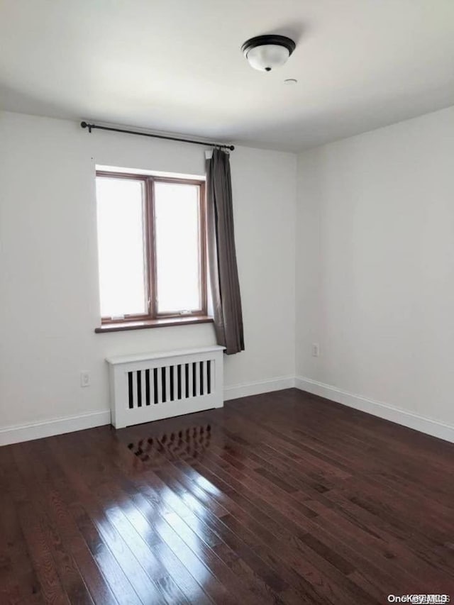 unfurnished room featuring dark hardwood / wood-style floors and radiator