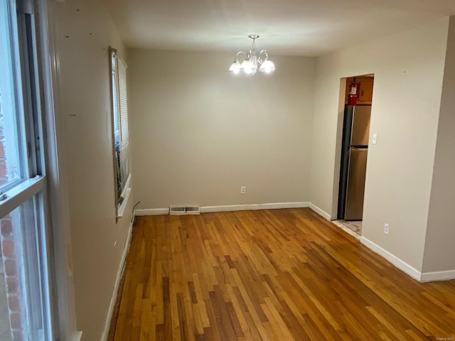 unfurnished room with light hardwood / wood-style floors and a chandelier