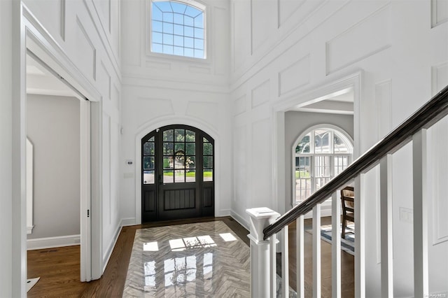 foyer featuring a towering ceiling and dark wood-type flooring