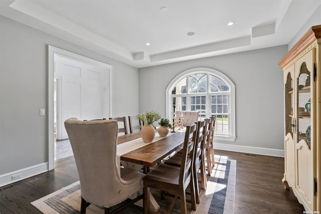 dining room with dark hardwood / wood-style floors and a raised ceiling