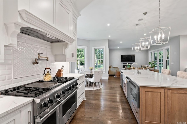 kitchen with a center island with sink, range with two ovens, light stone countertops, dark hardwood / wood-style flooring, and white cabinetry