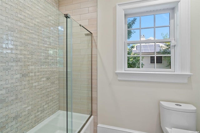 bathroom with toilet and combined bath / shower with glass door