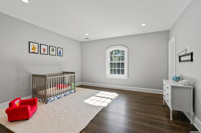 bedroom featuring a crib and dark hardwood / wood-style floors