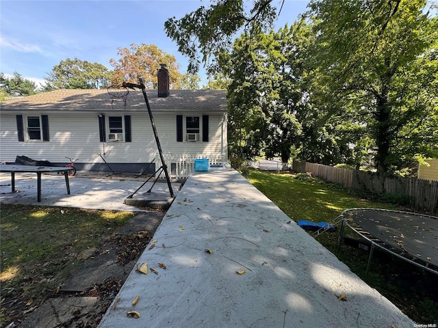 back of property featuring a yard, a trampoline, cooling unit, and a patio area