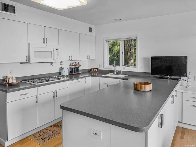 kitchen featuring sink, stainless steel gas cooktop, white cabinets, kitchen peninsula, and light wood-type flooring