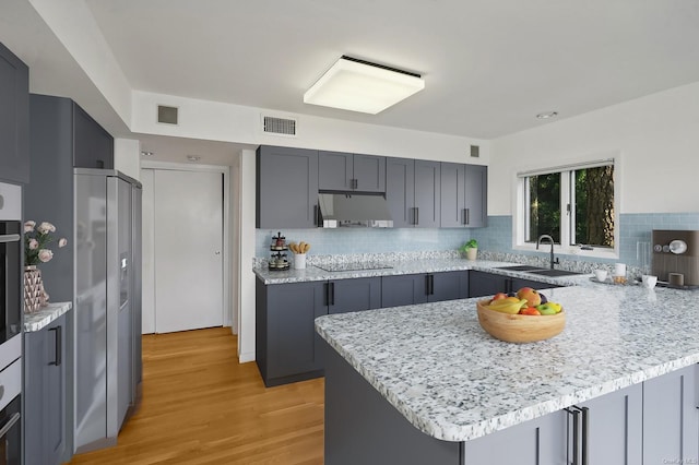 kitchen featuring black electric cooktop, light hardwood / wood-style floors, sink, and gray cabinetry