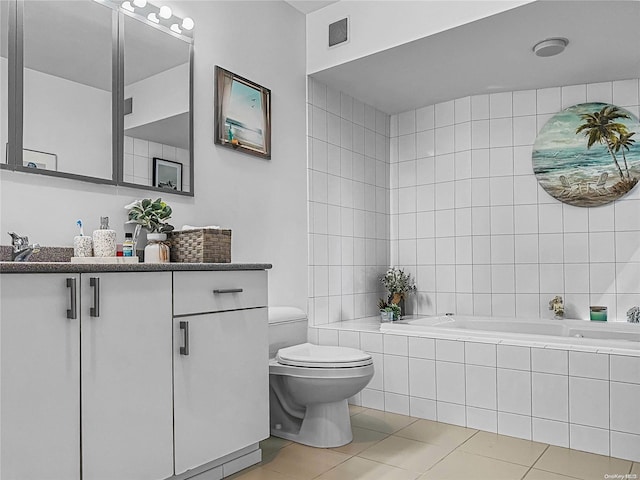 bathroom featuring a relaxing tiled tub, tile patterned floors, toilet, and vanity