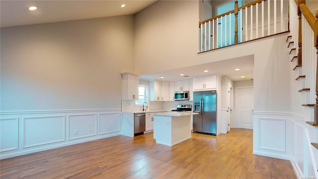 kitchen with a center island, sink, white cabinetry, light hardwood / wood-style flooring, and appliances with stainless steel finishes