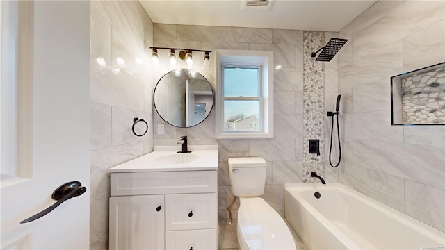 full bathroom with toilet, tile walls, vanity, and tiled shower / bath combo