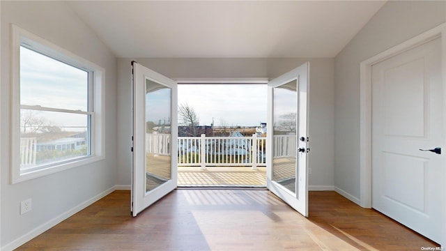 doorway featuring lofted ceiling, french doors, a wealth of natural light, and hardwood / wood-style floors