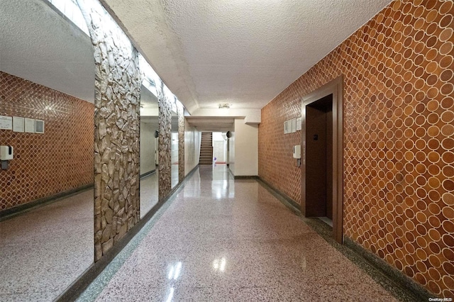 hall with a textured ceiling and elevator