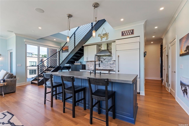 100 Garvies Point Rd Unit 1309, Glen Cove, NY 11542 - kitchen featuring wall chimney range hood, ornamental molding, dark countertops, decorative backsplash, and wood finished floors