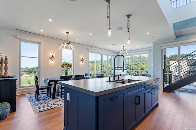 kitchen with hanging light fixtures, sink, a kitchen island with sink, and a wealth of natural light