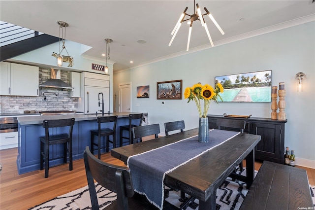 dining area featuring ornamental molding, light hardwood / wood-style flooring, a notable chandelier, and sink