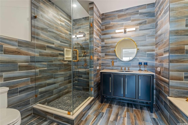 bathroom featuring walk in shower, vanity, toilet, and tile walls