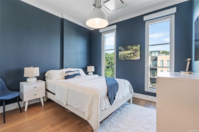 bedroom with multiple windows, crown molding, and hardwood / wood-style floors