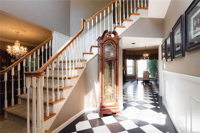stairway with a chandelier, a high ceiling, and ornamental molding