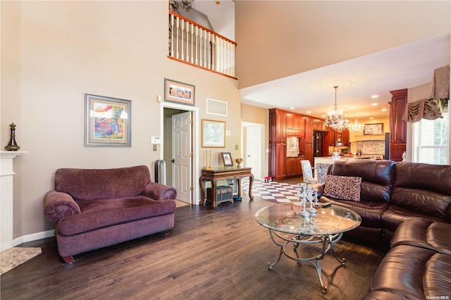 living room with a high end fireplace, a towering ceiling, an inviting chandelier, and dark wood-type flooring