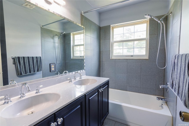 bathroom featuring tile patterned floors, vanity, a healthy amount of sunlight, and tiled shower / bath