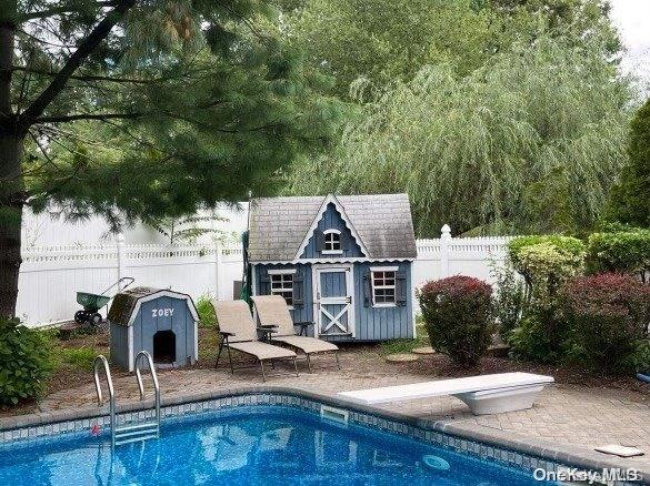 view of swimming pool featuring a storage unit, a diving board, and a patio area