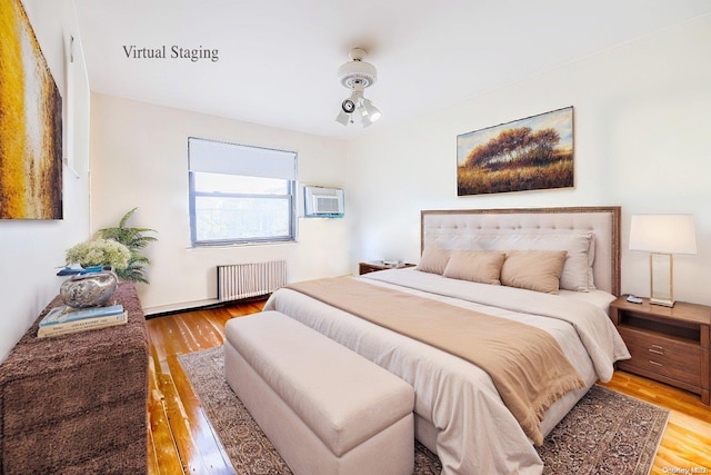 bedroom featuring a wall mounted AC, hardwood / wood-style floors, and radiator