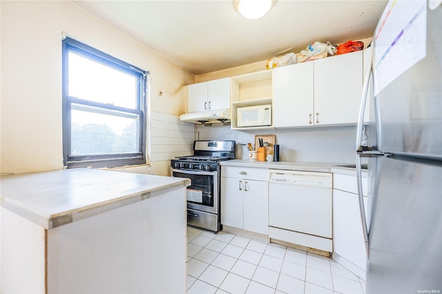 kitchen with stainless steel appliances, light tile patterned floors, kitchen peninsula, decorative backsplash, and white cabinets