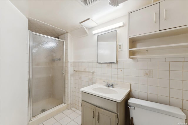 bathroom featuring tile patterned flooring, an enclosed shower, toilet, vanity, and tile walls