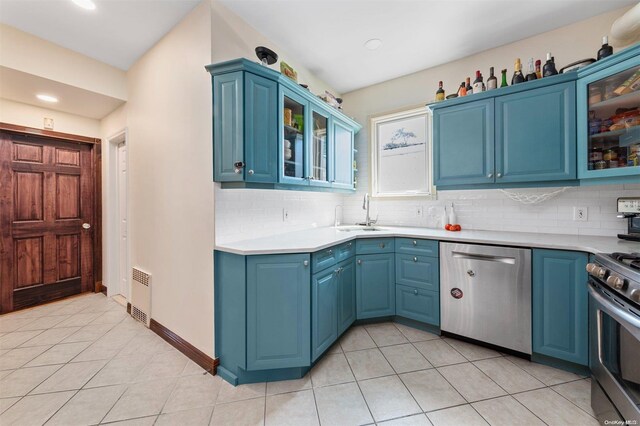 kitchen with appliances with stainless steel finishes, tasteful backsplash, blue cabinets, and sink