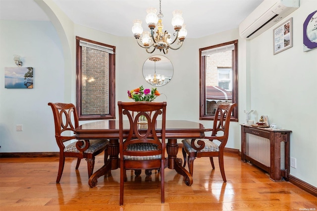 dining space with a chandelier, light hardwood / wood-style floors, and a wall mounted AC