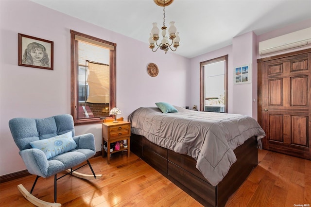 bedroom with an inviting chandelier, light hardwood / wood-style floors, and a wall unit AC