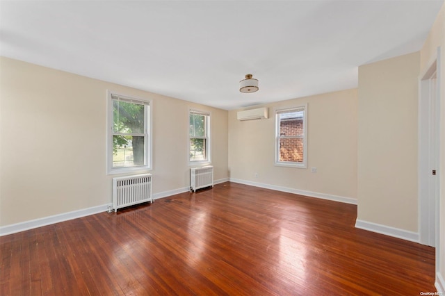 unfurnished room featuring a wall unit AC, radiator, and dark wood-type flooring