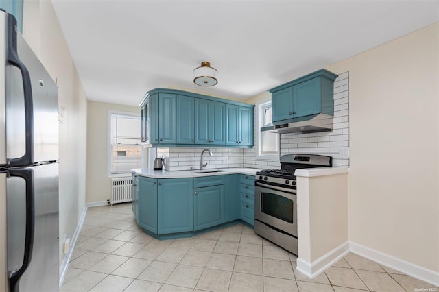 kitchen with decorative backsplash, radiator heating unit, blue cabinetry, and appliances with stainless steel finishes